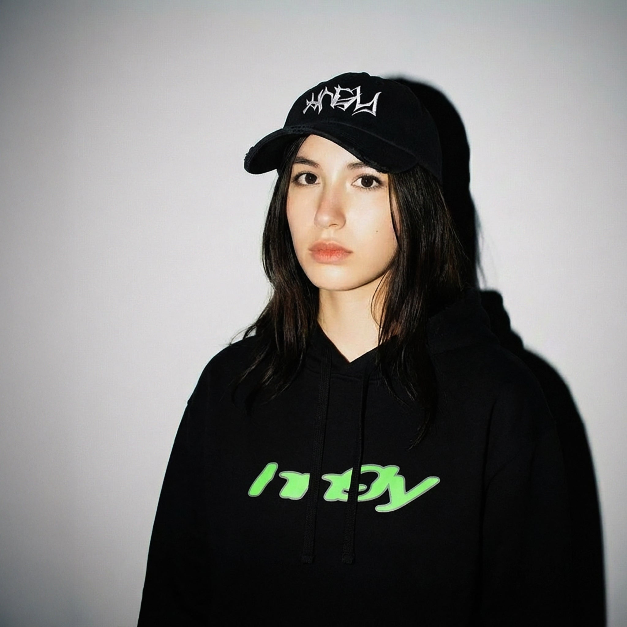 Person wearing a black HNGY hoodie with neon green logo on a neutral background