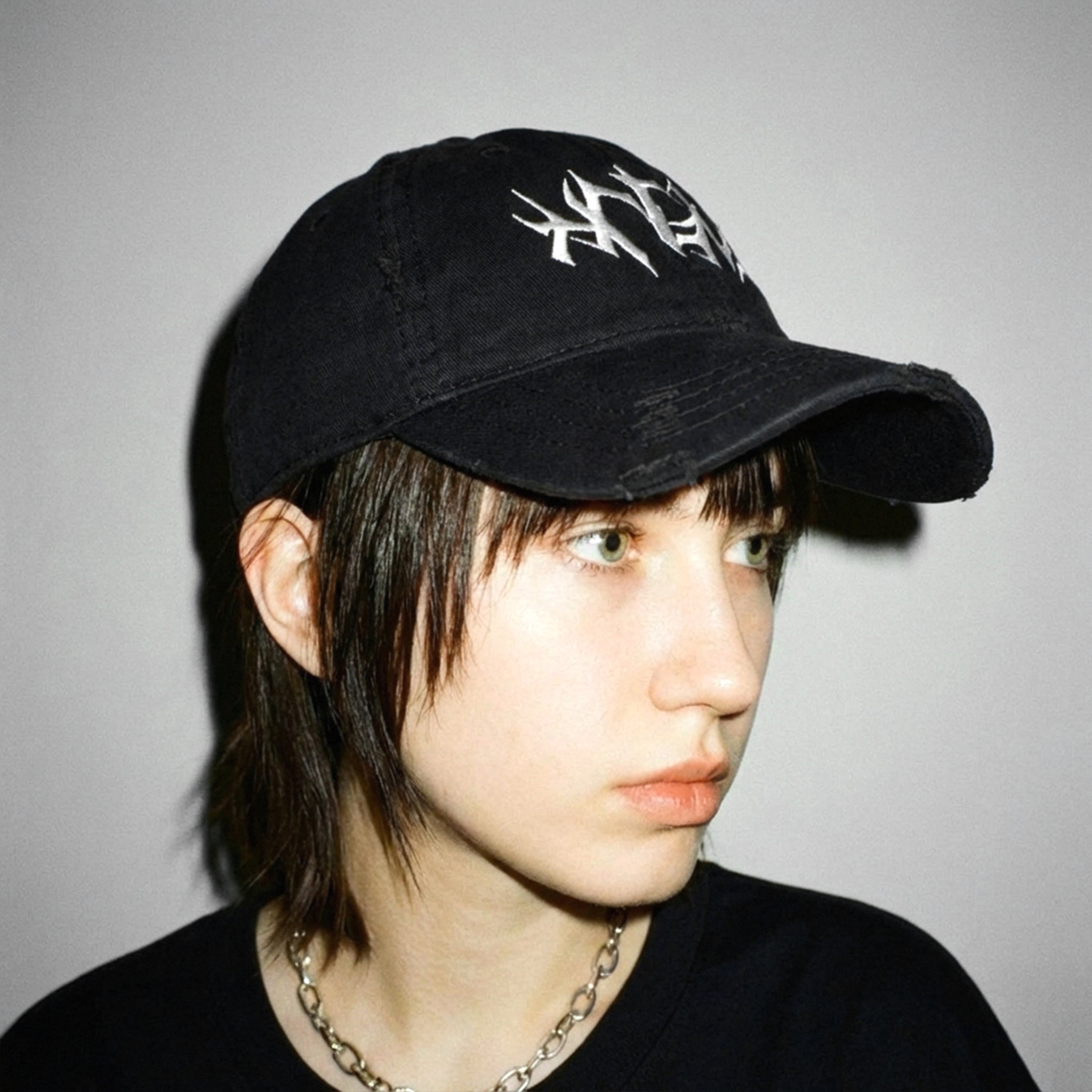 Side profile of the HNGY Distressed Bold Cap with white embroidered design.