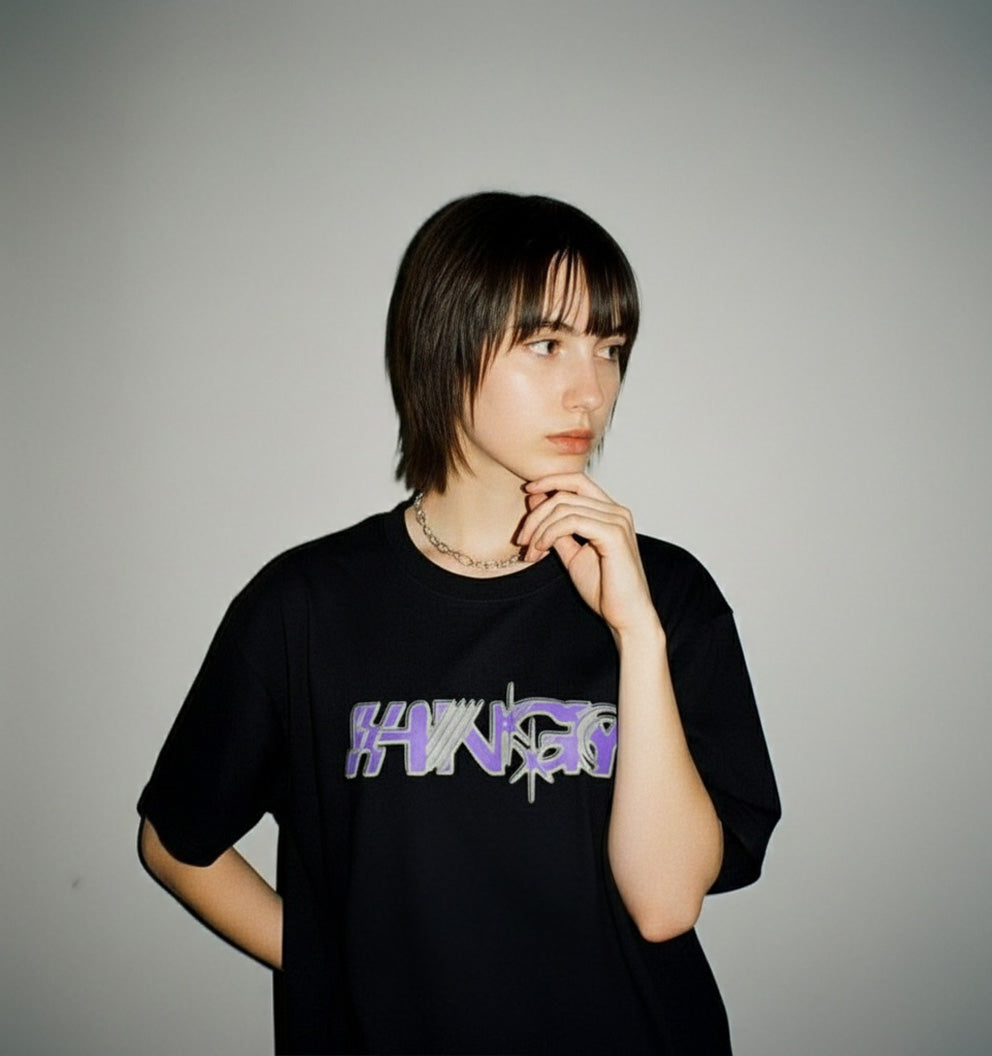 Person wearing the HNGY oversized black t-shirt with purple graffiti logo, front view
